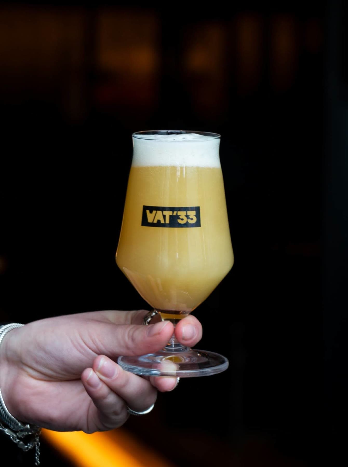 Een VAT'33-glas met troebel bier, in de hand gehouden